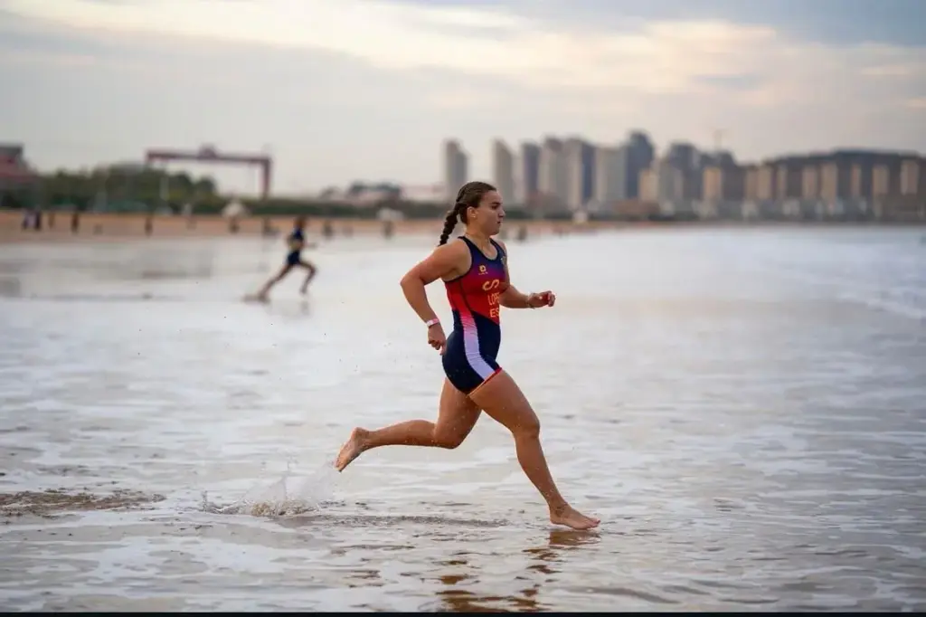 Blanca López Valera sale corriendo del mar por la playa durante el Mundial de Beach Sprint, con los edificios de Qingdao al fondo