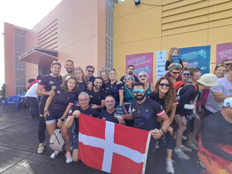 Integrantes del equipo de dragon boat del Club Náutico Santa Lucía posan con la bandera de Cartagena ante los carteles del VIII Jan Collins Memorial e Intercontinental Dragon Boat Festival en San Pedro del Pinatar